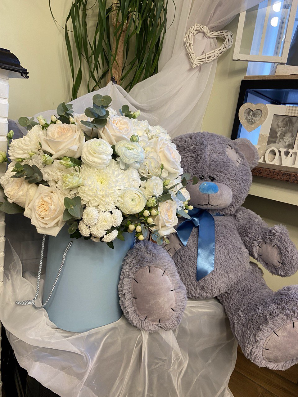 Elegant hatbox flower arrangement with white roses, ranunculus, hydrangeas, chrysanthemums and eucalyptus, creating a fresh and timeless design.