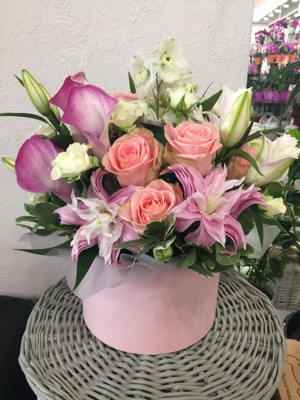Delicate flower box arrangement featuring pink lilies, peach roses, white spray roses and purple calla lilies, styled in a soft pink designer box.