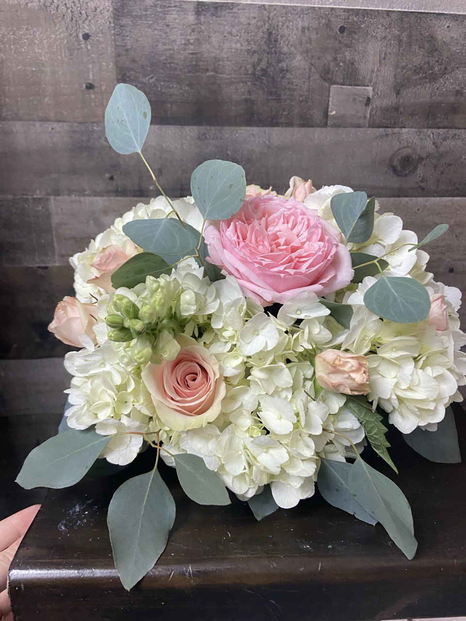 Elegant wedding flower arrangement featuring blush pink roses, white hydrangeas, lisianthus, and eucalyptus greenery, styled in a soft romantic design.