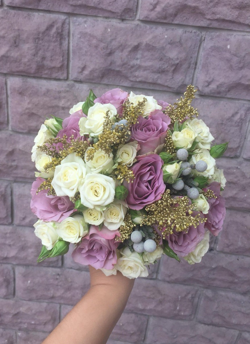 Bridal bouquet Aphrodite featuring soft lavender and cream roses, accented with golden fillers and silver brunia, creating an elegant and luxurious wedding arrangement