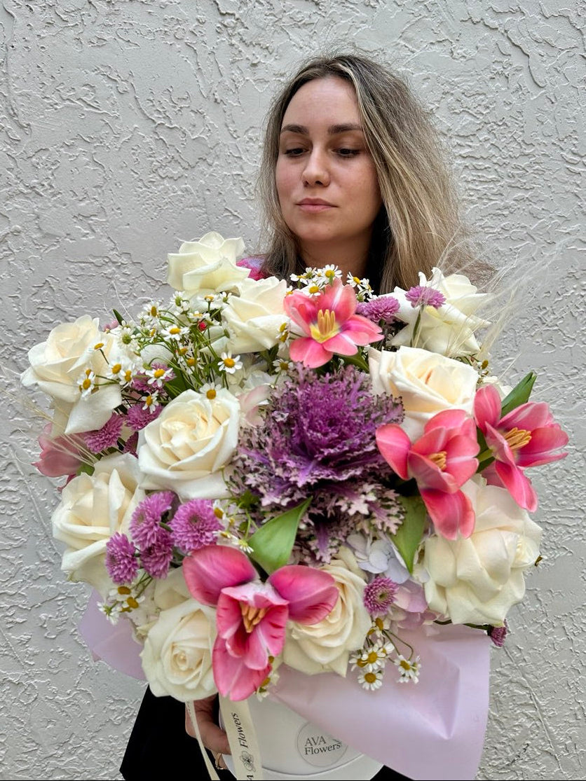 Woman holding a large bouquet of flowers against a plain background