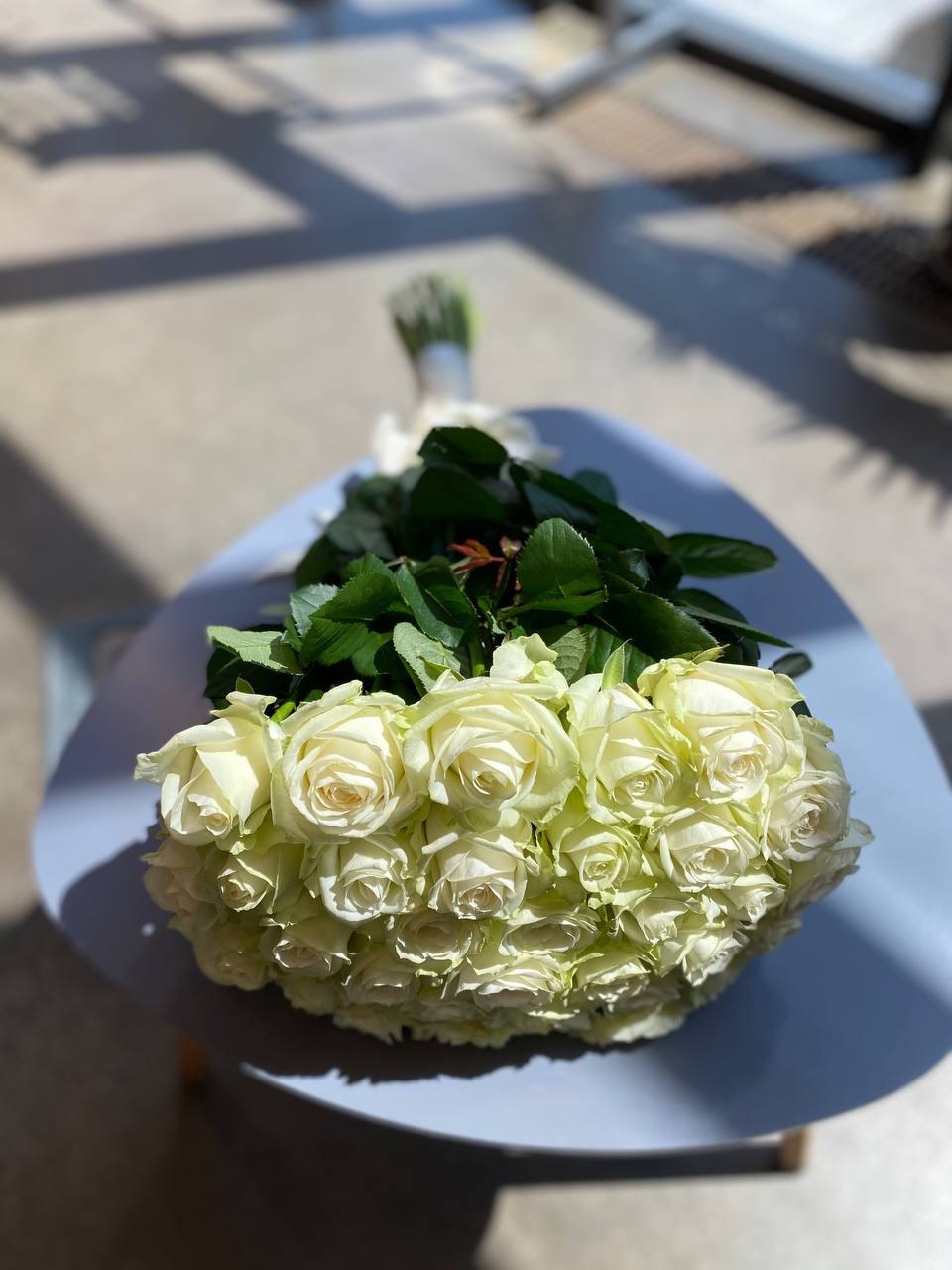 Elegant bouquet of fresh white roses, wrapped in minimalist paper, perfect for weddings, anniversaries, or special occasions.