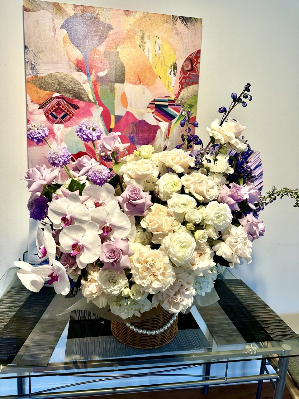 Bouquet of flowers on a glass table with colorful abstract art in the background