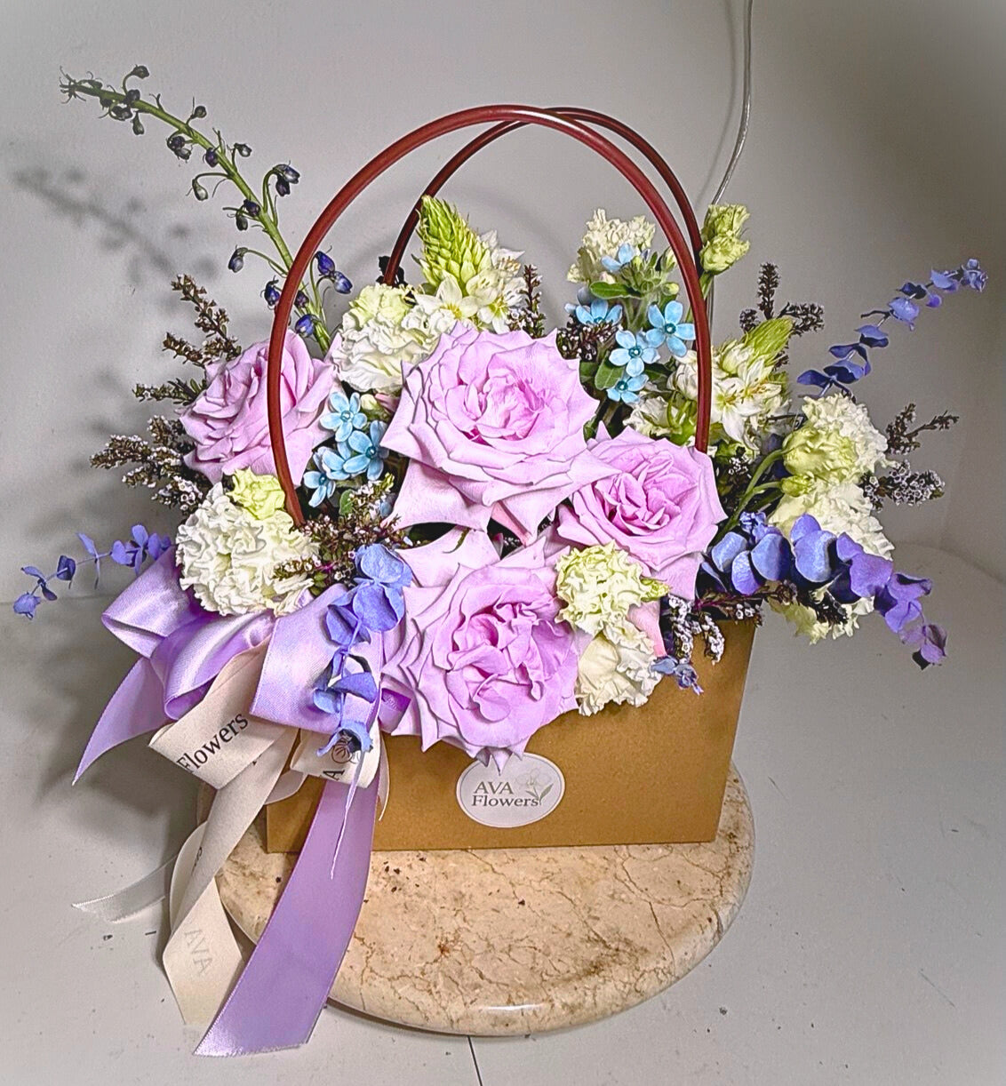 Floral arrangement in a basket with pink and white flowers on a marble stand.