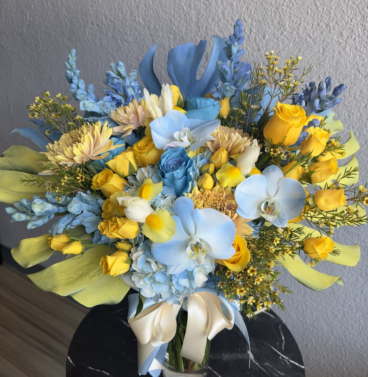 Bright bouquet inspired by Ukrainian colors, featuring blue hydrangeas, yellow roses, chrysanthemums and tulips, accented with greenery and tied with satin ribbons.