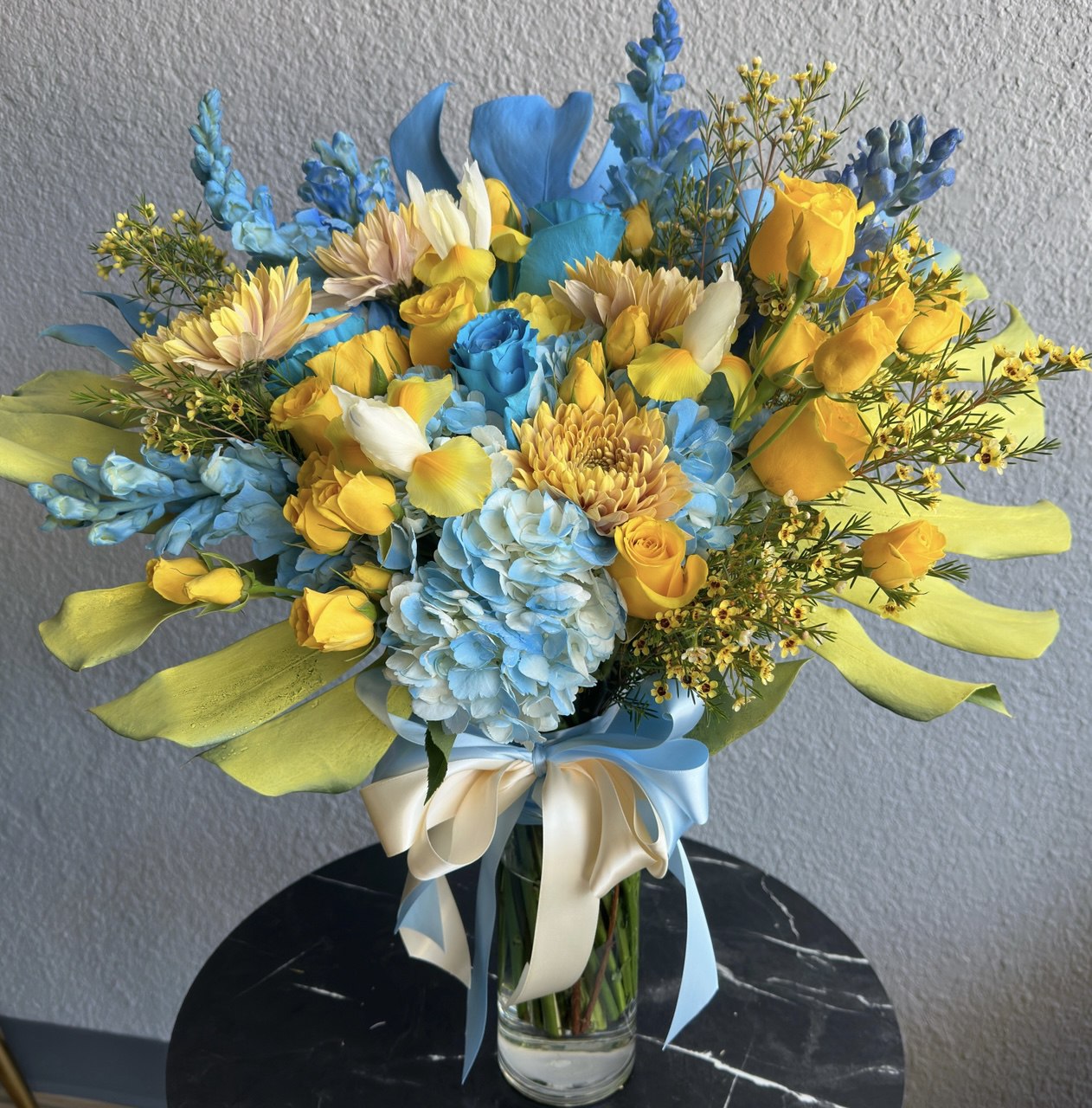 Bright bouquet inspired by Ukrainian colors, featuring blue hydrangeas, yellow roses, chrysanthemums and tulips, accented with greenery and tied with satin ribbons.