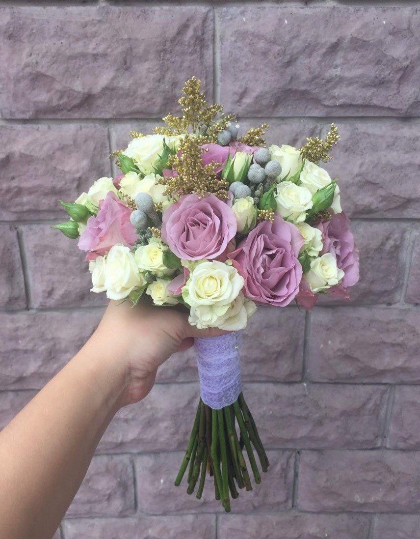 Bridal bouquet Aphrodite featuring soft lavender and cream roses, accented with golden fillers and silver brunia, creating an elegant and luxurious wedding arrangement