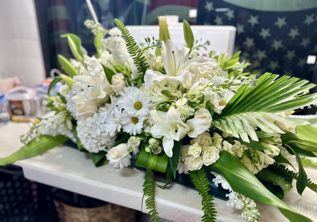 Funeral arrangement “Eternal Rest” with white lilies, roses, daisies, and lush greenery — an elegant sympathy flower display for honoring loved ones.