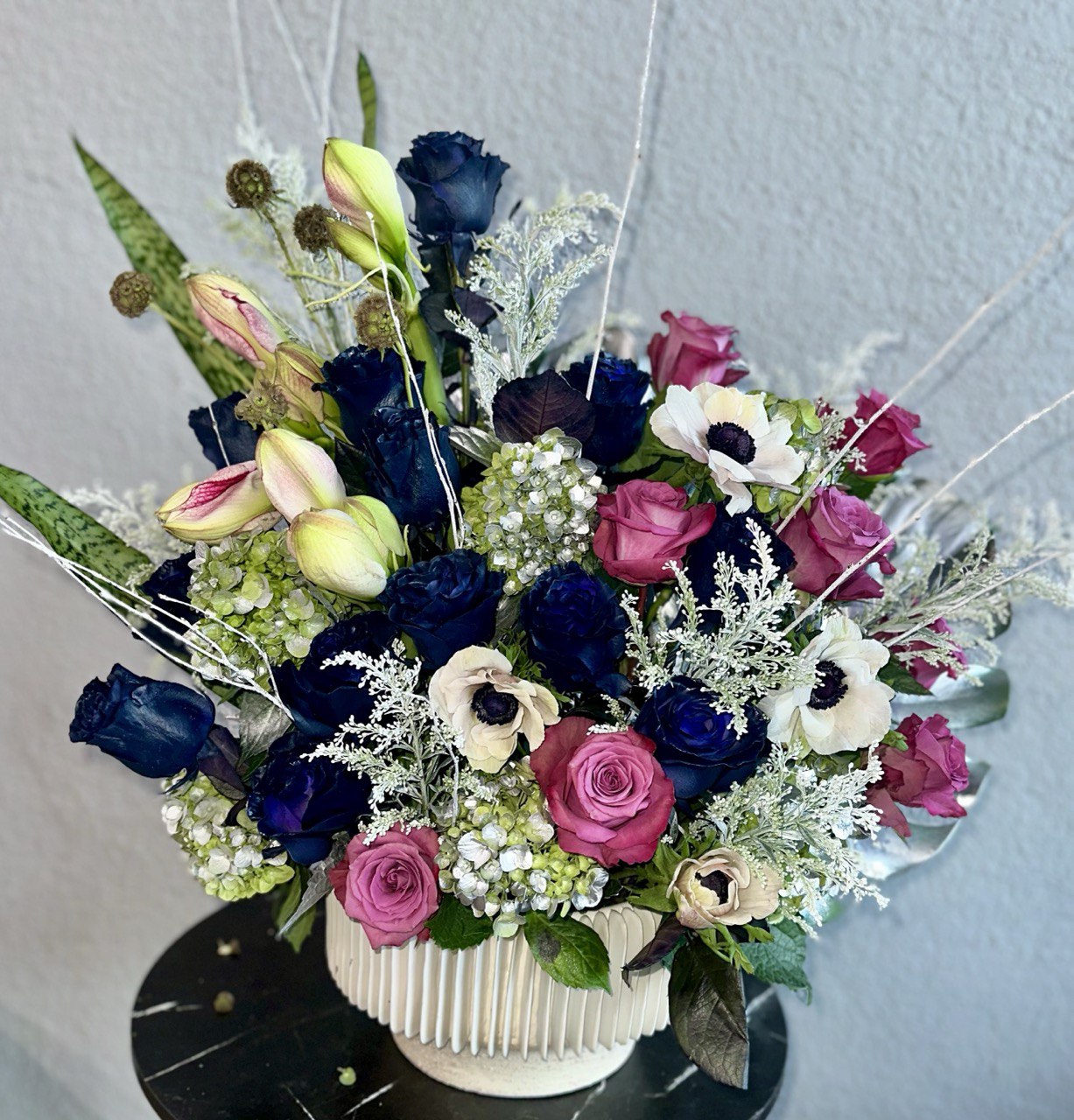 Bouquet of flowers with blue, pink, and white roses on a light gray background