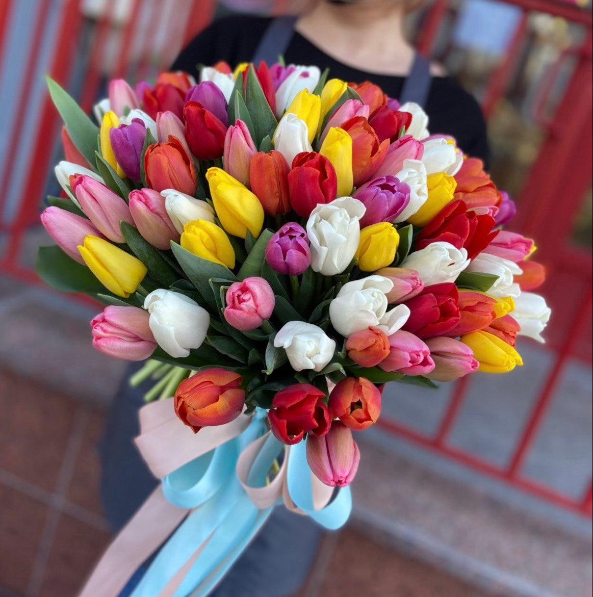 Bouquet of multicolored tulips held by a person with a blurred background