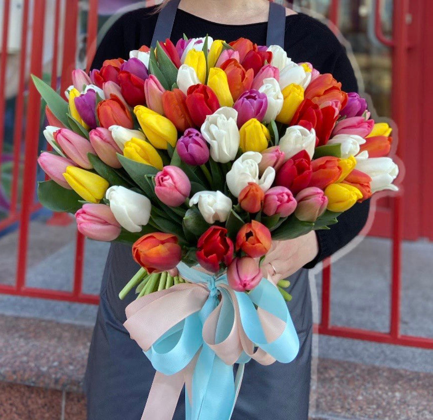 Bouquet of colorful tulips held by a person with a blurred background