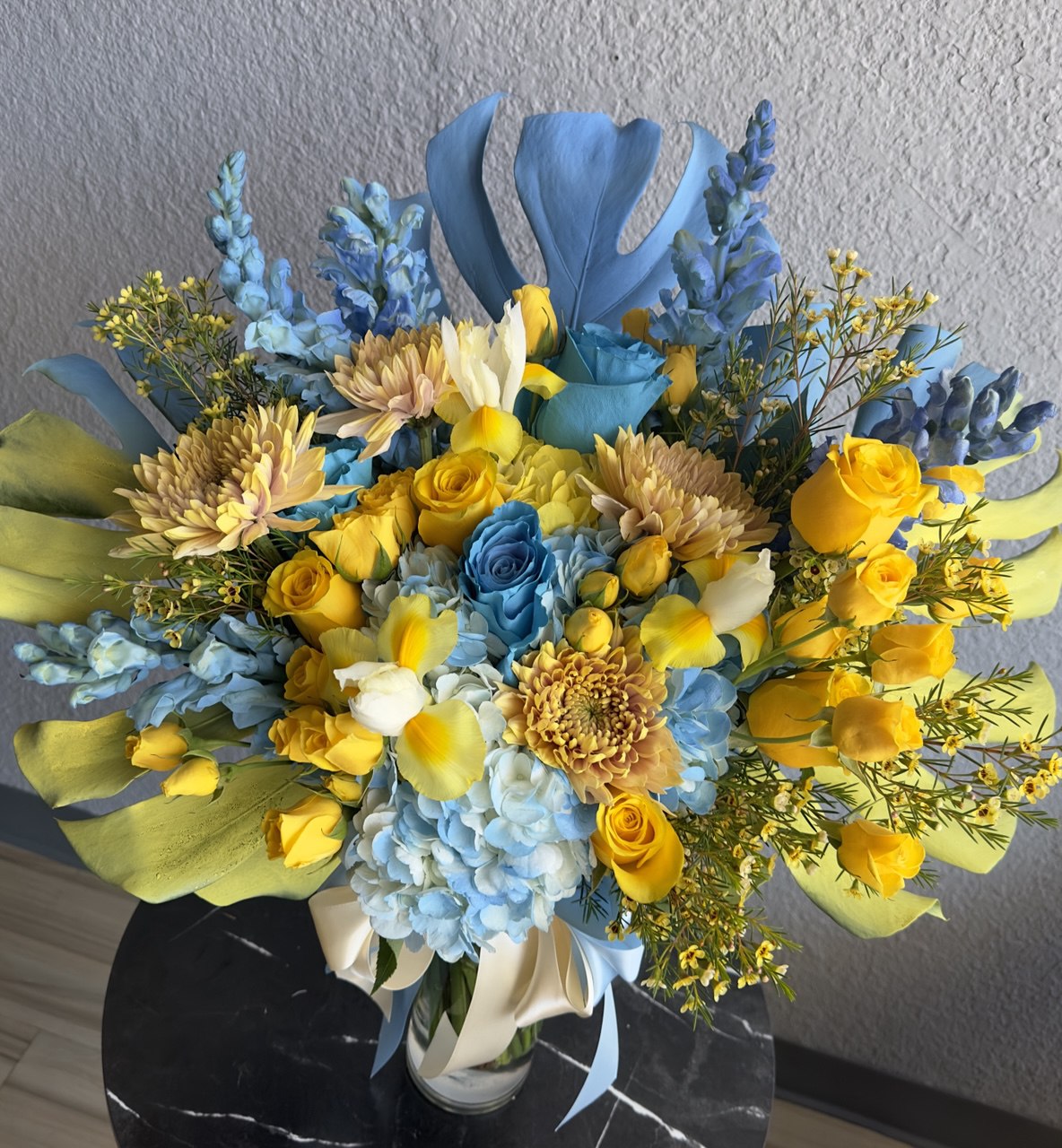 Bright bouquet inspired by Ukrainian colors, featuring blue hydrangeas, yellow roses, chrysanthemums and tulips, accented with greenery and tied with satin ribbons.