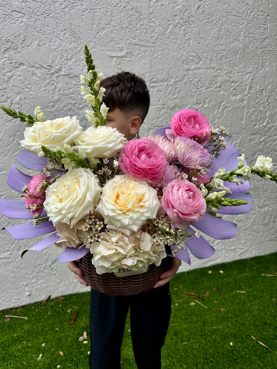 Person holding a large bouquet of flowers against a plain wall.