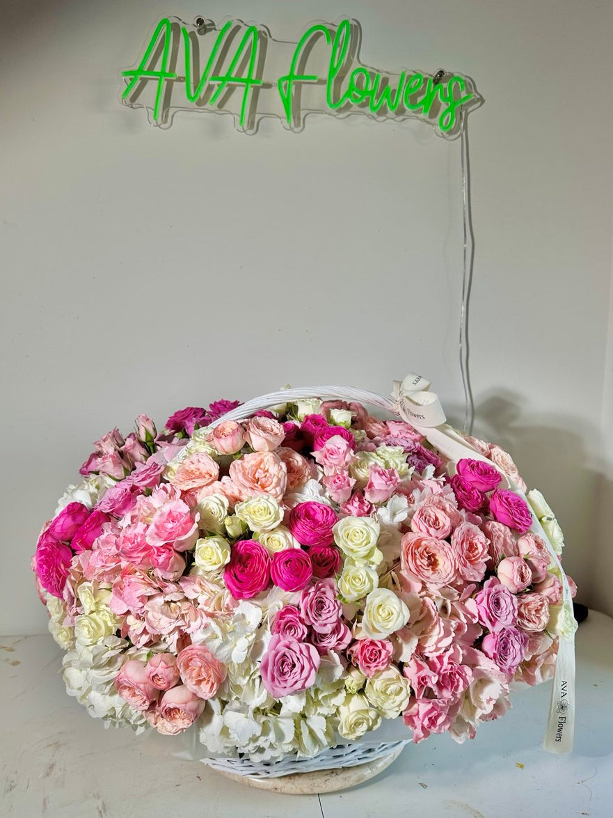 Basket of pink and white flowers with a neon sign reading 'AVA Flowers' in the background.