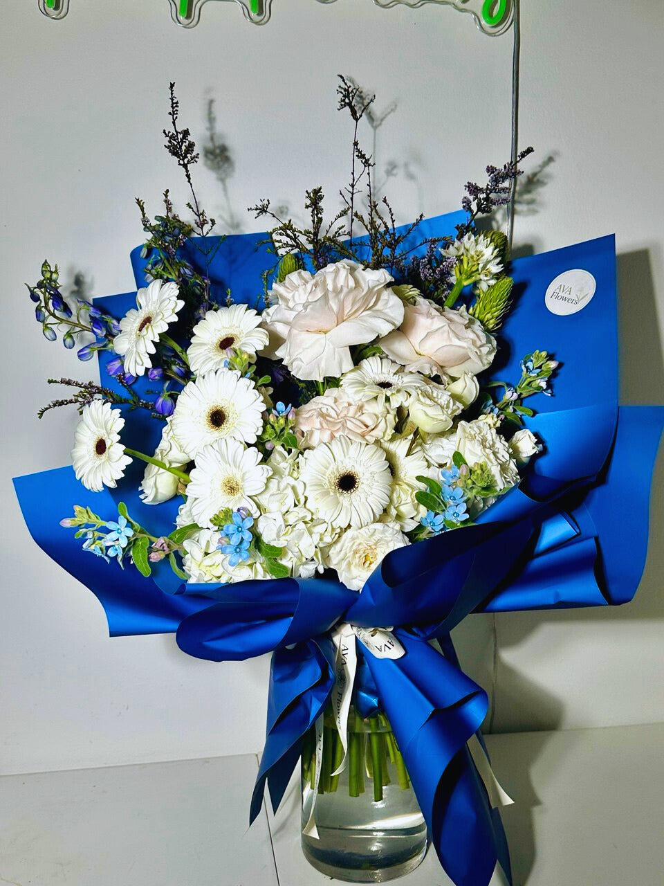 Bouquet of flowers with a blue ribbon in a clear vase on a white background