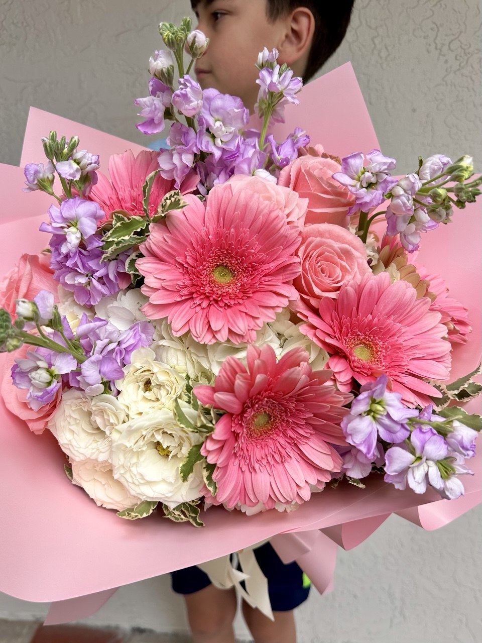 Bouquet of pink, white, and purple flowers with a child in the background