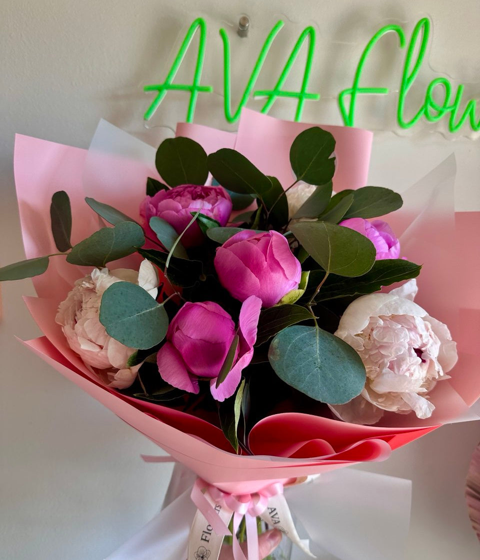 Bouquet of flowers with pink and green accents, branded 'AVA flow', on a white background.