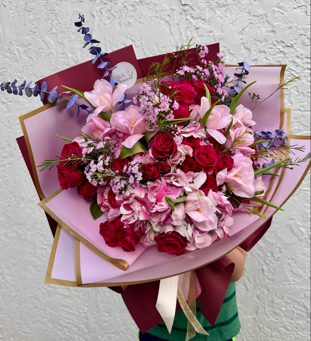 Bouquet of flowers wrapped in pink paper with a white background