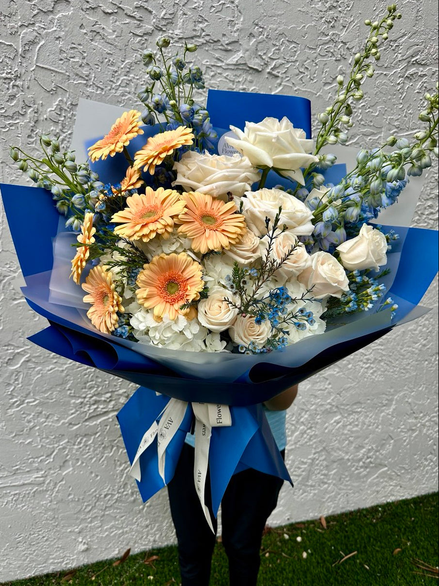 Bouquet of flowers with blue wrap against a white wall