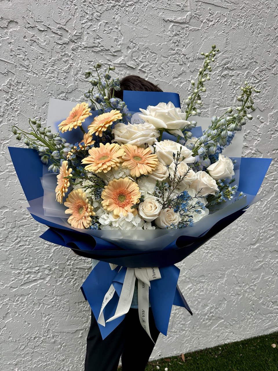 Bouquet of flowers with blue wrap against a gray wall