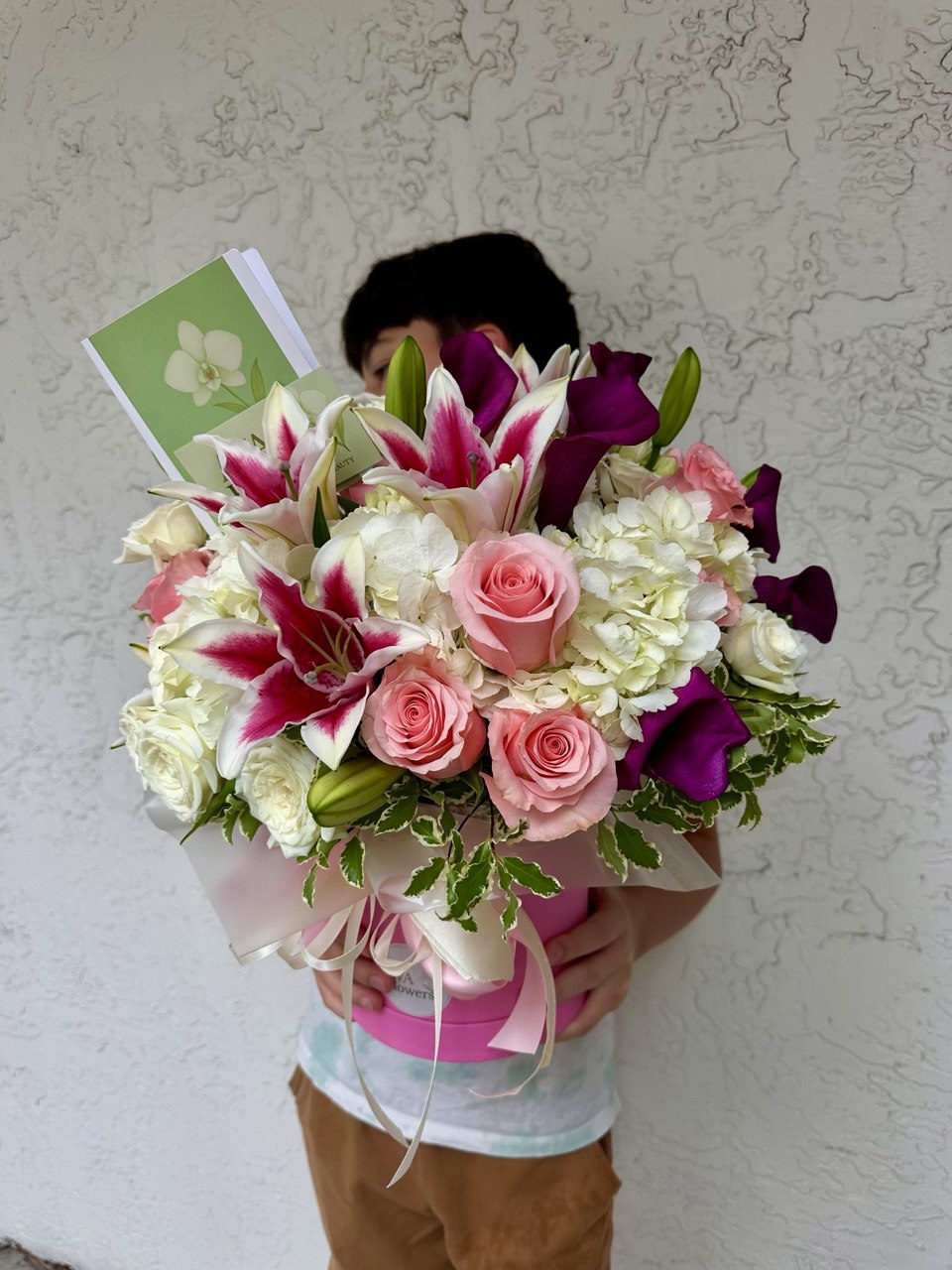 Person holding a bouquet of flowers against a textured wall.