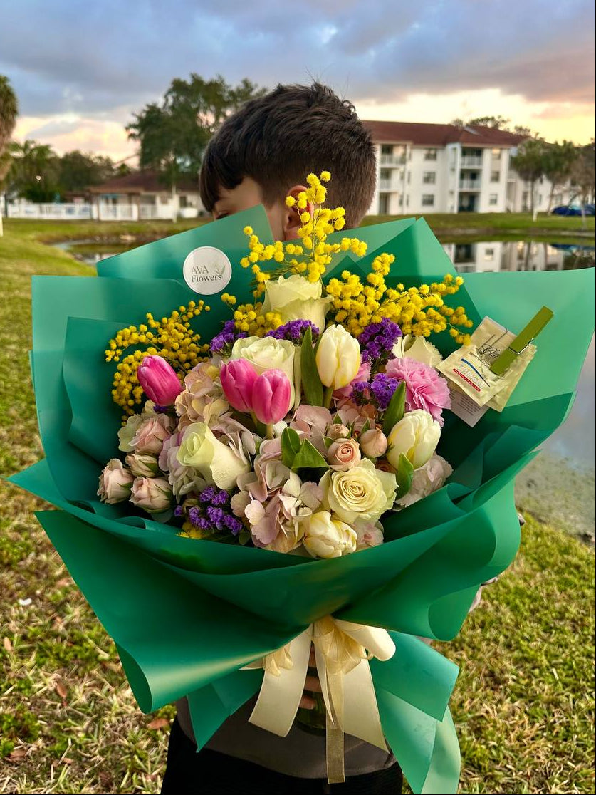 Person holding a large bouquet of flowers outdoors with a scenic background