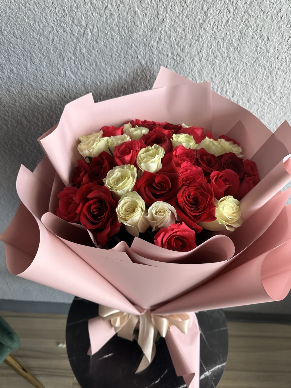 Romantic bouquet with fresh red and white roses, arranged in soft pink designer wrapping and tied with a satin ribbon, symbolizing love and elegance.