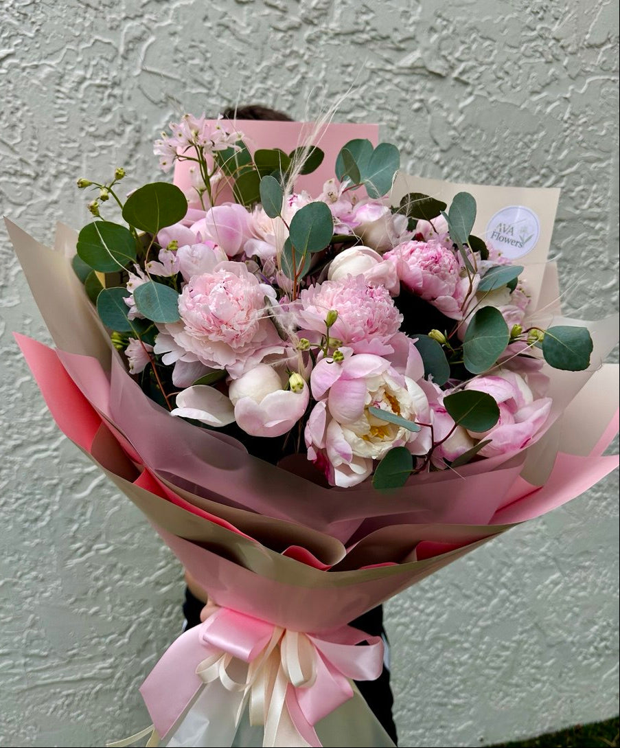 Bouquet of pink flowers with green leaves on a light gray background