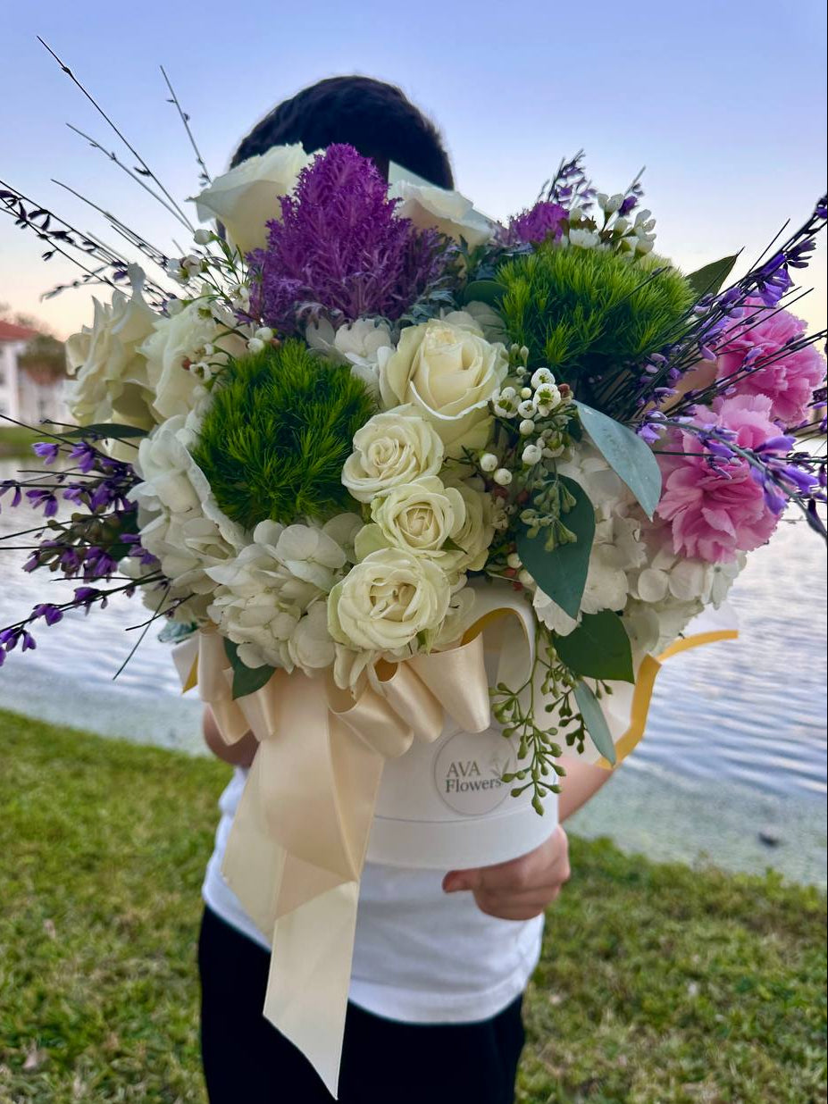 Person holding a bouquet of flowers by a body of water
