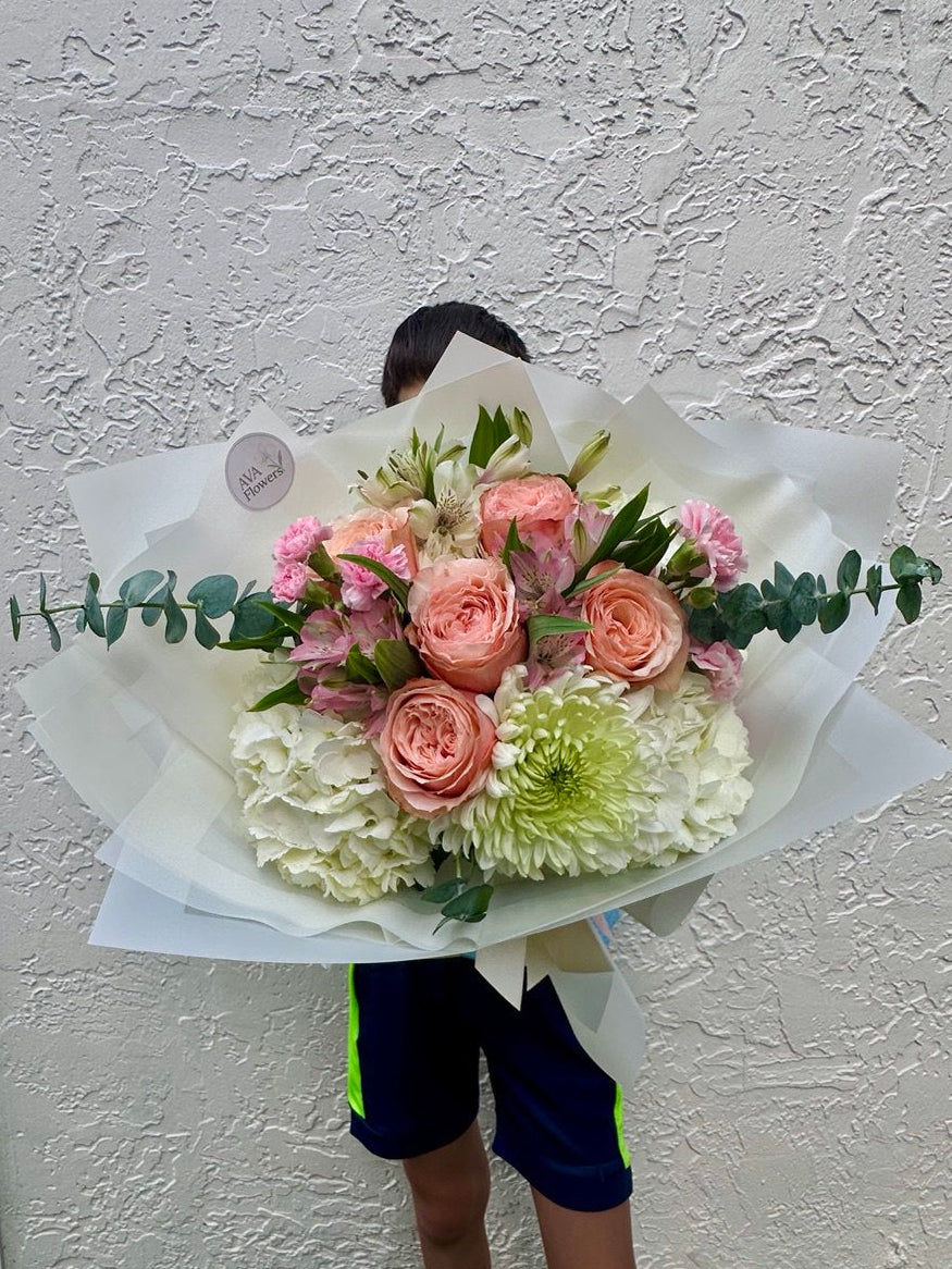 Person holding a bouquet of flowers against a textured wall