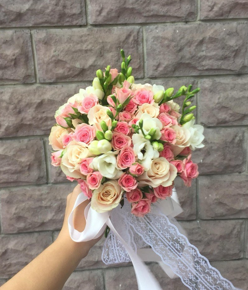 Bridal bouquet “Anna” with blush roses, pink spray roses, and white freesia, tied with satin ribbon and lace — elegant wedding flowers in medium size.